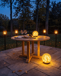 Luxent Hosting Set — 4 solar flame torches and 2 garden orbs arranged around a patio dinner table at dusk