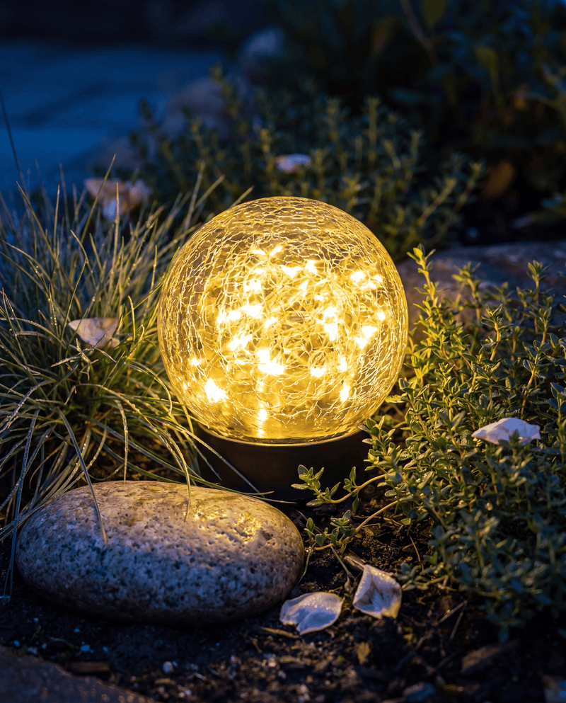 Luxent Crackle solar garden orb glowing amber on a patio table at dusk