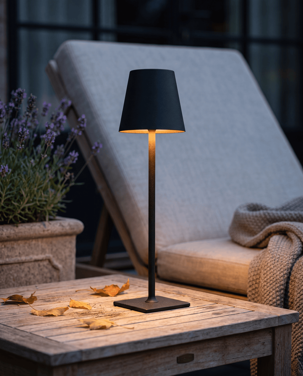 Luxent cordless tabletop lantern with a matte finish glowing on an outdoor dinner table