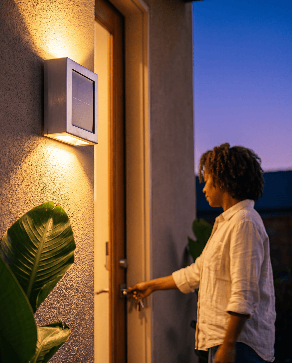 Luxent solar wall sconce casting an architectural up-and-down wash of light on an exterior wall